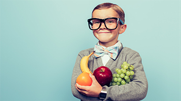Child wearing glasses and holding produce.